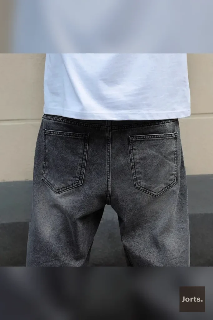 Side profile of men's gray straight-leg cropped denim shorts, highlighting the relaxed fit and cropped length.